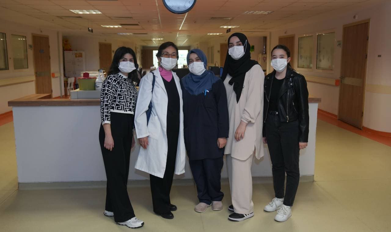 Masked healthcare workers and student volunteers in a hospital corridor